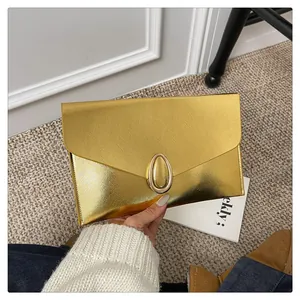 Close-up of golden envelope clutch bag with brushed metal texture and oval buckle