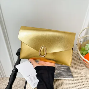 Elegant gold metallic envelope clutch with oval lock and textured finish in hand