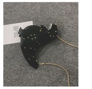 Close-up of black dinosaur crossbody bag featuring gold studs and metal chain strap