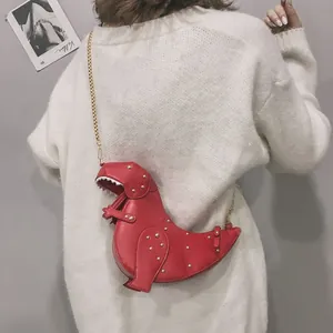 Detail of red dinosaur crossbody bag with gold studs and chain strap on a white sweater