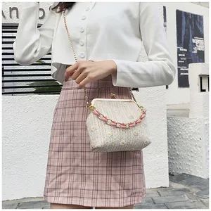 Dettaglio di una mini borsa in paglia con margherite ricamate e catena in resina rosa