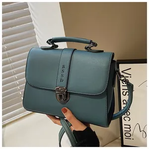 Detail van blauwgroene PU-lederen handtas met vintage sluiting en reliëflogo