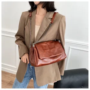 Caramel brown quilted crossbody bag shown on model with metal chain and leather strap