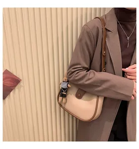 Detail van beige crossbodytas met konijnenhanger en goudkleurige metalen details