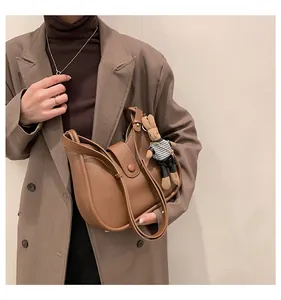 Bruine halve maan zadeltas met een schattige konijnenhanger gedragen door een model