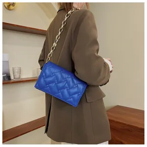 Royal blue quilted leather shoulder bag with chunky gold chain strap worn by a model
