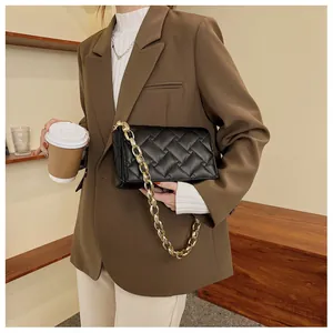 Detail of black quilted shoulder bag with thick gold chain on a fashion model