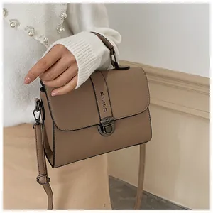 Detail van vierkante crossbodytas met metalen draaisluiting en verstelbare riem
