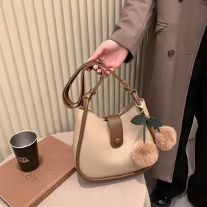 Modieuze beige lederen halve maan handtas met bruine rand en kersen hanger detail