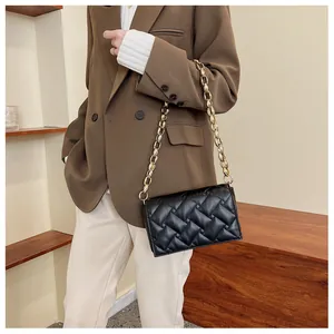 Detailed view of black quilted crossbody bag featuring large chunky gold chain strap