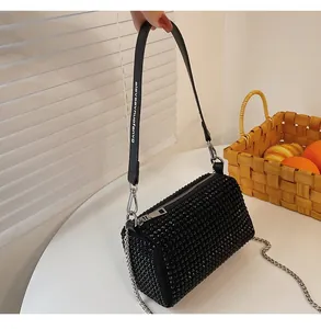 Close-up of black rhinestone cylinder bag featuring a wide strap and silver chain detail
