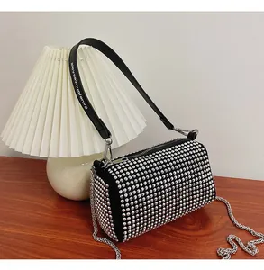 Detail of a black cylinder bag with silver rhinestones and adjustable metal chain strap