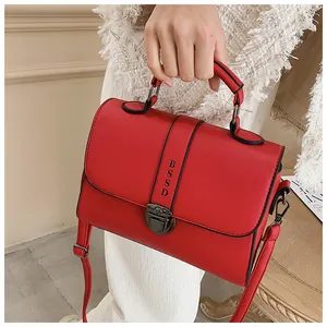 Detail van rode vierkante crossbodytas met vintage slot en getextureerde kunstlederen riem