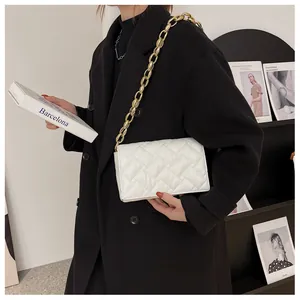 Detail of white quilted handbag featuring premium stitching and bold gold chain strap