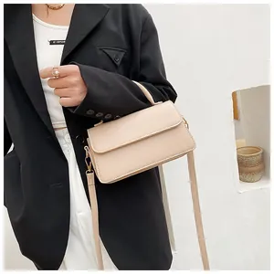 Sac bandoulière en cuir beige porté, avec poignée supérieure et sangle réglable
