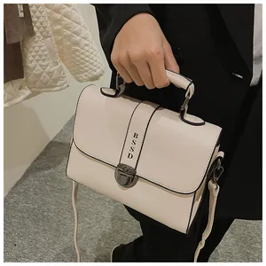 Detail van de roomwitte crossbodytas met zwarte bies en vintage metalen gespsluiting