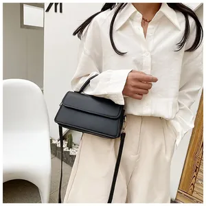 Détails d'un sac bandoulière minimaliste en cuir noir avec boucles métalliques dorées