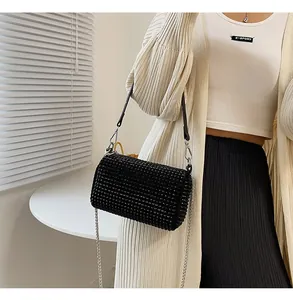 Close-up of sparkling black rhinestone cylinder bag with silver metal chain strap