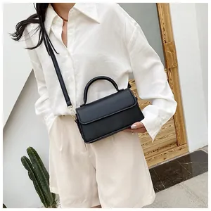 Sac à main carré noir minimaliste porté avec une tenue d'été pour femme