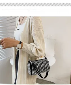 Fashionable black rhinestone cylinder bag with silver chain and logo strap on model