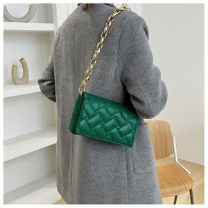 Detail of bright green quilted shoulder bag with bold gold chain strap on grey coat