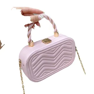 Light pink quilted box bag with a spiral handle and gold chain strap on white background