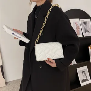 White quilted crossbody bag with gold chain strap shown on a model in a stylish setting
