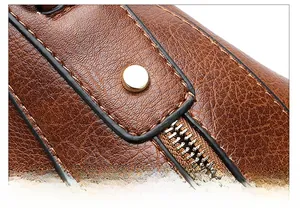 Details der braunen Ledertasche mit Lychee-Muster, Ziernähten und goldenen Nieten