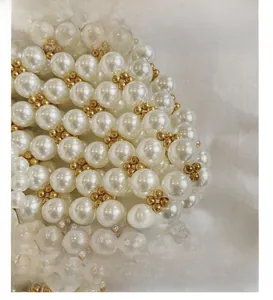 Macro shot of handcrafted white pearls and gold metal beads on a vintage clutch bag