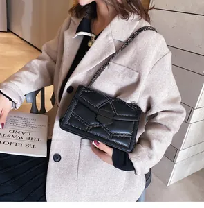 Détail d'un sac à bandoulière en cuir noir matelassé avec clous et chaîne en métal