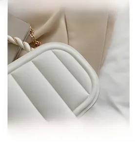 Detail of white quilted handbag showing soft fabric texture and gold chain strap