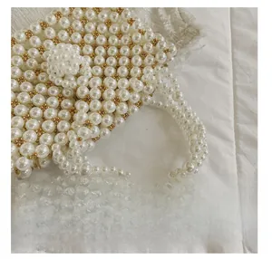 Detail presentation of handmade pearl handbag featuring woven diamond pattern with gold beads
