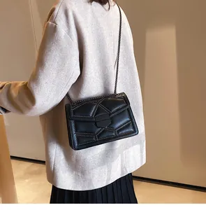 Détail d'un sac bandoulière noir matelassé avec rivets métalliques porté par un mannequin