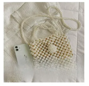 Detailed view of handmade pearl mini bag next to a phone for size comparison
