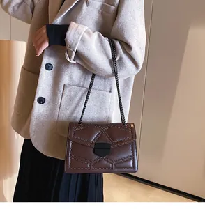 Détail du sac bandoulière matelassé marron foncé avec clous et chaîne élégante