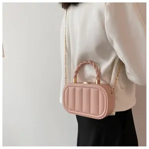 Side view of pink quilted box bag with gold chain strap on model in formal wear