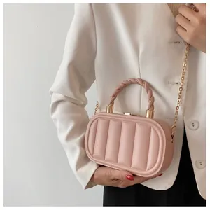 Detail view of pink quilted handbag with gold chain strap worn by a model in white