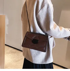 Détails du sac bandoulière marron foncé avec clous et coutures géométriques