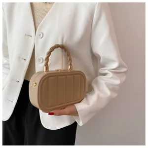 Detail of khaki oval hardshell bag with quilted vertical stripes and twist handle