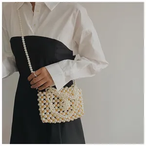 Detail of handmade pearl shoulder bag featuring a woven CC logo and beaded strap