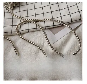 Detail of silver beaded metal chain with mirror finish on black and white plaid cloth