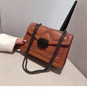 Détail du sac en similicuir ambre avec motif clouté et bandoulière en chaîne foncée