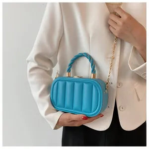 Detail of bright blue quilted handbag with rope handle and gold chain strap