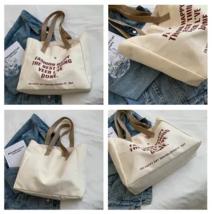 Detail view of large canvas tote bag with burgundy lettering and brown handles