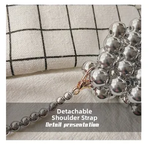 Detail of silver beaded bag with a shiny removable shoulder strap and golden metal clasp