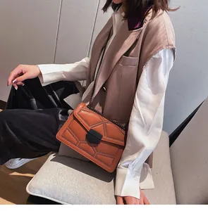Vue détaillée du sac bandoulière marron avec rivets noirs et boucle en métal géométrique