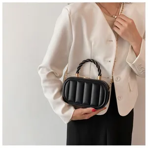 Close-up of black textured crossbody bag with rope handle and gold chain strap on a model
