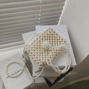 Elegant handmade pearl woven handbag with a central statement bead and crossbody chain strap