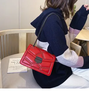 Détail du sac bandoulière en cuir rouge avec rivets noirs et bandoulière en chaîne