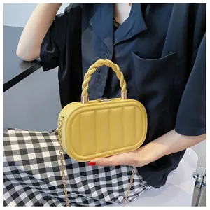 Detail of yellow quilted oval box bag with twisted handle and golden metal chain